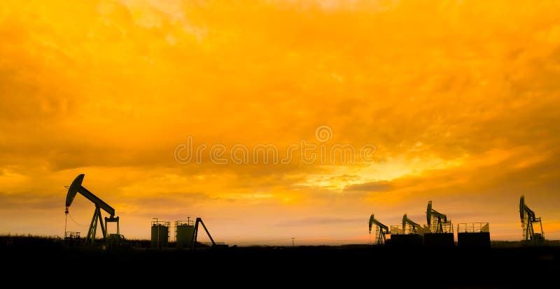 Oil pumps at oil field with sunset sky background