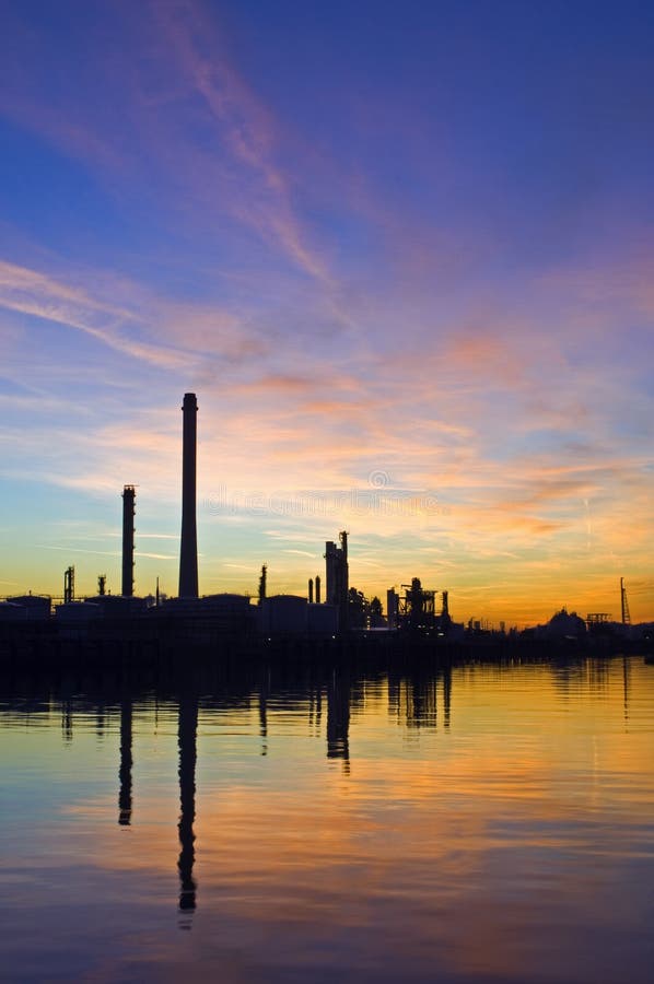 La silhouette di una raffineria di petrolio al tramonto, contro una radiosa del cielo.