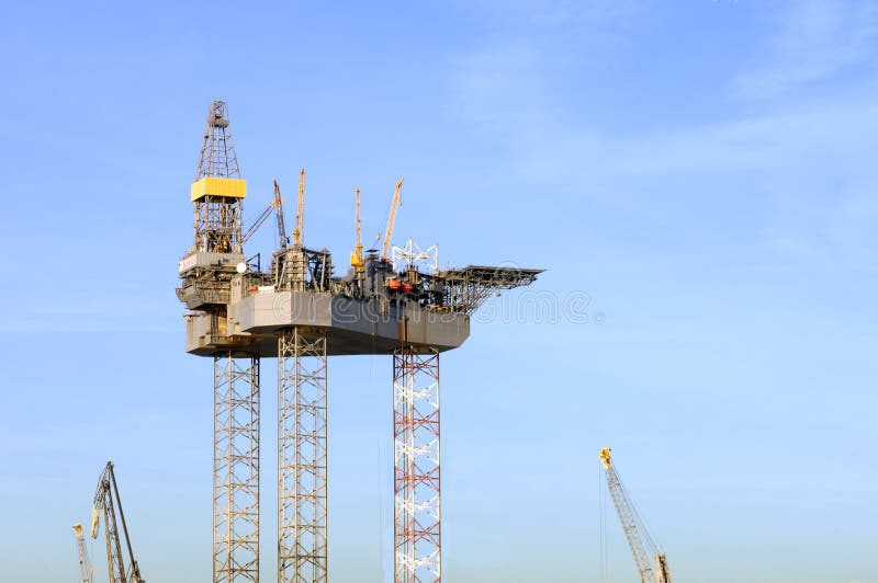Oil rig construction. An oil rig is being constructed in a harbor area, to be towed to sea after completion. This image is part of the collection royalty free stock image Oil rig construction. An oil rig is being constructed in a harbor area, to be towed to sea after completion. This image is part of the collection royalty free stock image
