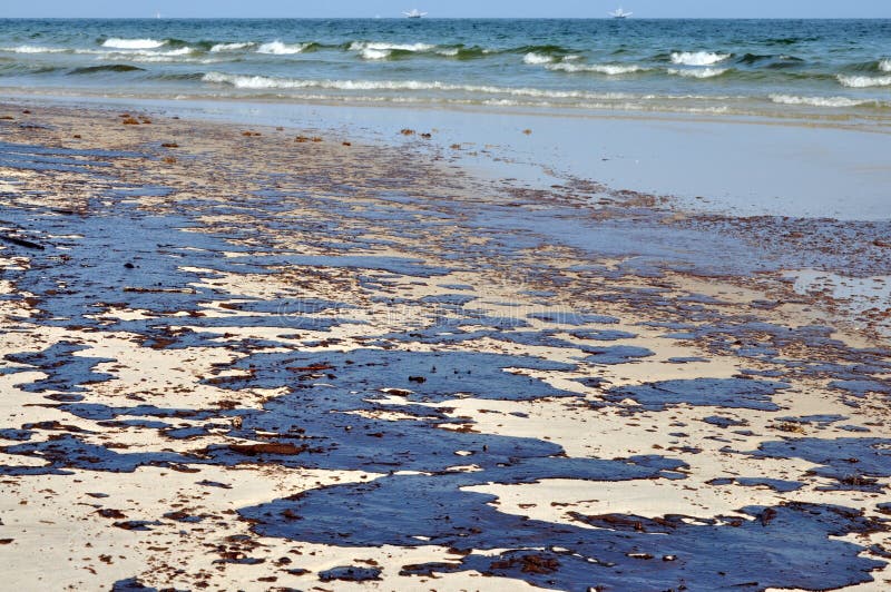 La fuoriuscita di petrolio sulla spiaggia con olio skimmer in background.