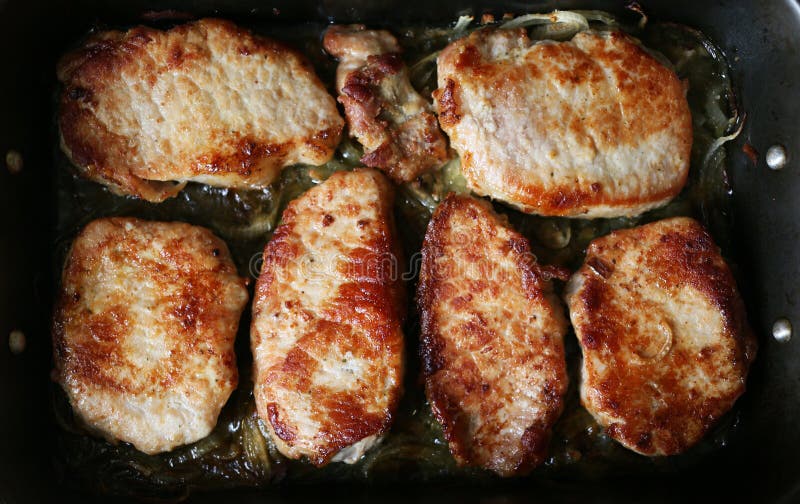 Oily fried pieces of pork with onions fried in the pan stock images