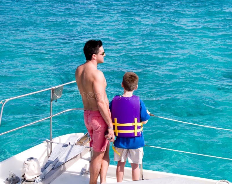 Father and son watching the Caribbean sea from the stern of a pleasure boat. Father and son watching the Caribbean sea from the stern of a pleasure boat.