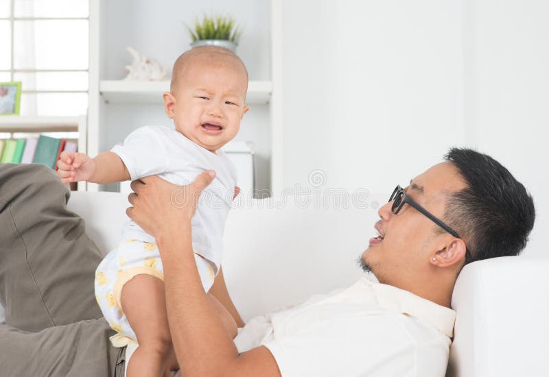 Asian family lifestyle at home. Father comforting crying baby boy. Asian family lifestyle at home. Father comforting crying baby boy.