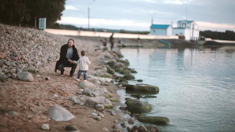 Ojciec, syn na plażowych mienie rękach i odprowadzenie wzdłuż brzeg przy zmierzchem Dziewczyna bieg obsługiwać Ojciec ściska córk