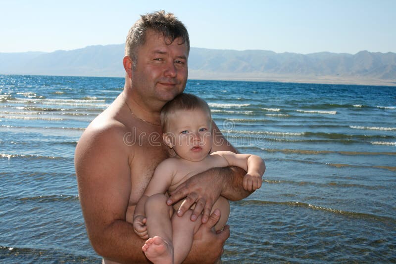 Father hold his son on his one's arms at the beach and smiling. Father hold his son on his one's arms at the beach and smiling