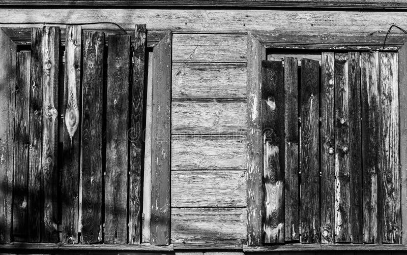 Monochrome image of windows of abandoned old wooden house hammered with planks. Monochrome image of windows of abandoned old wooden house hammered with planks