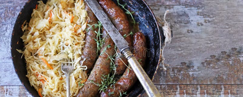 Oktoberfest food. Bavarian sausages and sauerkraut in a pan.