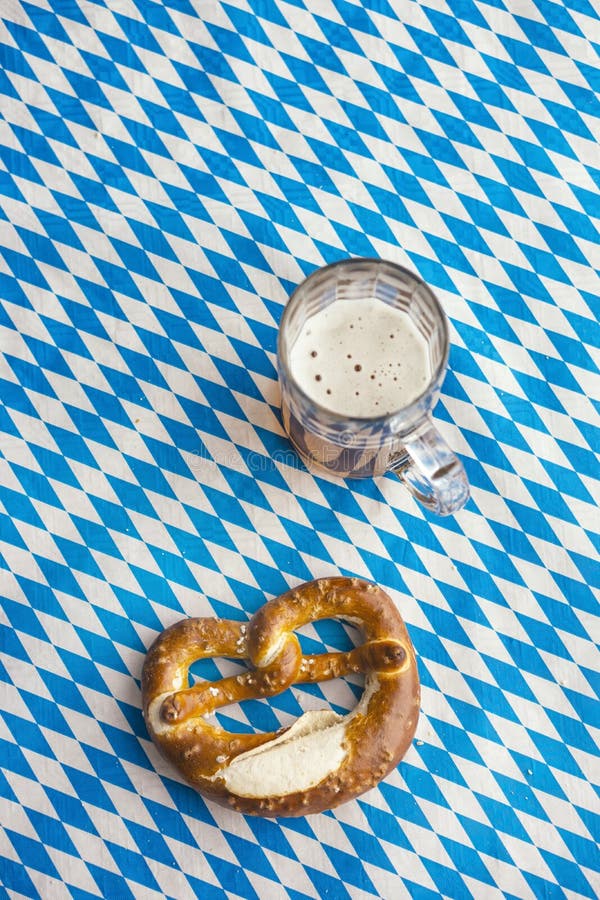 Oktoberfest: Pretzel e cerveja na toalha de mesa bávara foto de stock royalty free Oktoberfest: Pretzel e cerveja na toalha de mesa bávara foto de stock royalty free
