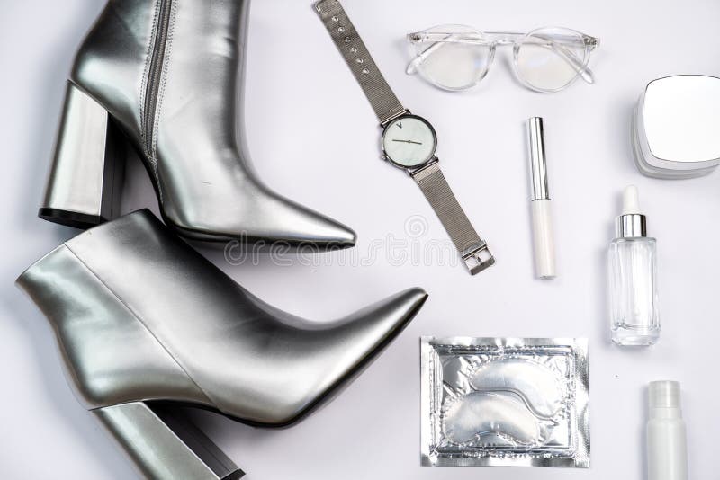 trendy stylish flat lay in silver colour: eye patches, glasses for vision, wrist watch, cream, serum, mascara and silver heels on a white background. trendy stylish flat lay in silver colour: eye patches, glasses for vision, wrist watch, cream, serum, mascara and silver heels on a white background