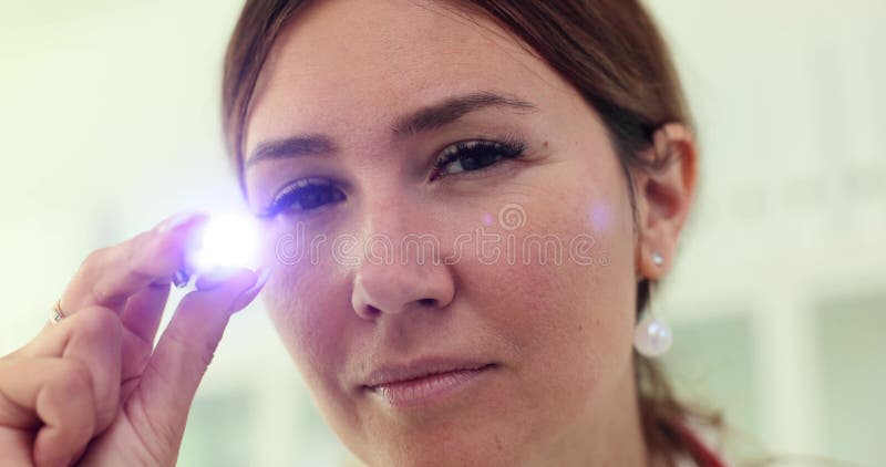 Okulista kobiet rzuca światło na kamerę