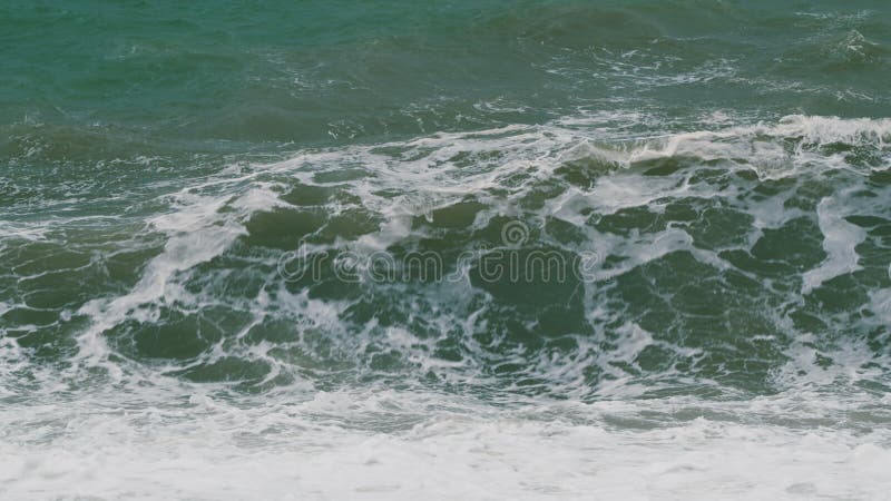 Olas que rompen sobre peligrosas olas de viento en la playa. potencia de las ondas rompiendo salpicaduras.