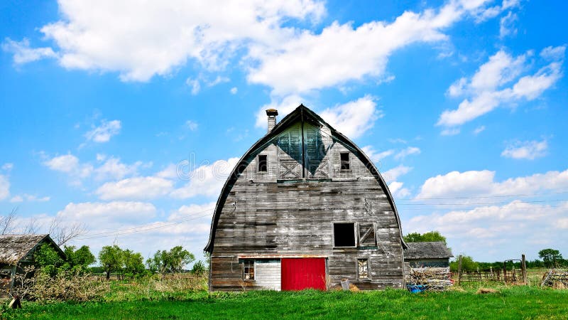 An old abandoned barn sits decaying on an empty farm