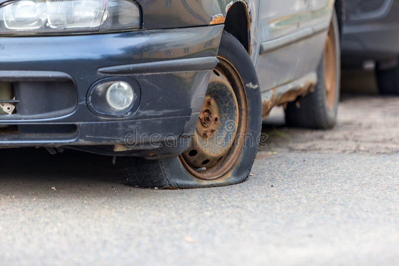 Old abandoned car with a rusting bottom and a flat wheel. Disposal and recycling of waste. Old rusty abandoned car with a flat tire stock photo Old abandoned car with a rusting bottom and a flat wheel. Disposal and recycling of waste. Old rusty abandoned car with a flat tire stock photo