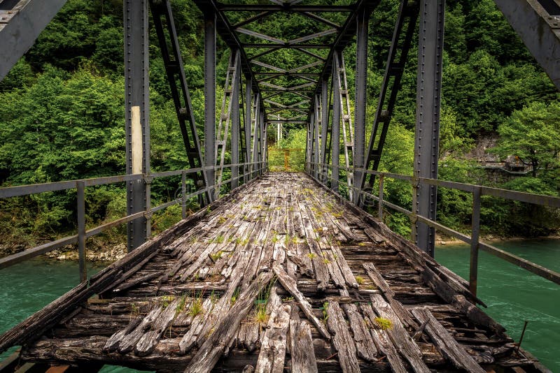 Old abandoned iron bridge spans over green river