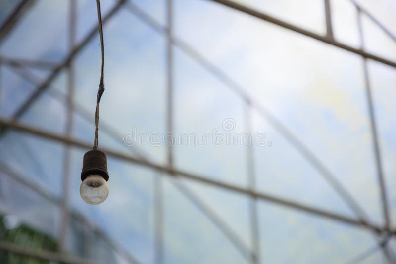 Old aged hanging incandescent light bulb in the industrial agriculture greenhouse background. indoor artificial lighting equipment