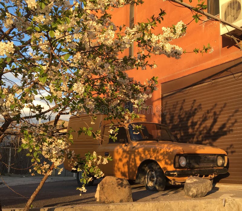 Old Aged Yellow Historical Classic Car Parked in Front of a House Stock