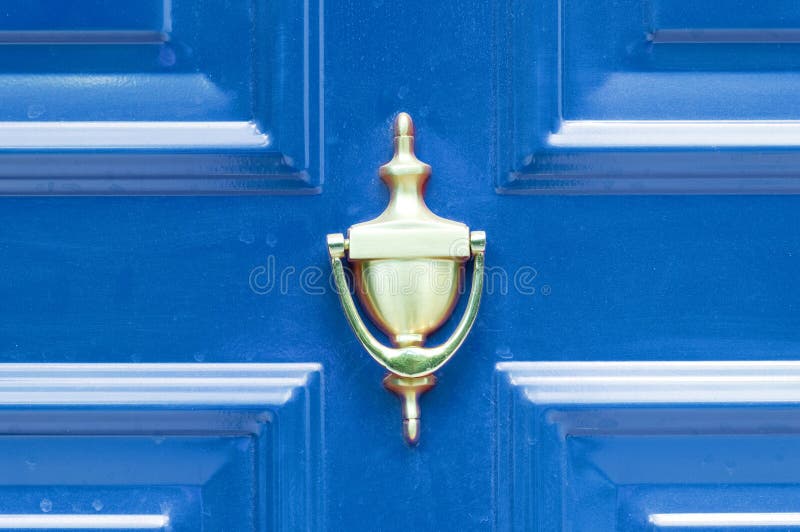 Old antique golden brass knocker on the abstract colored wooden doors for knocking close up