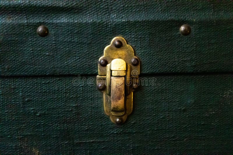 Old antique golden metal lock on green textile suitcase, close-up. Vintage retro styled textured toned