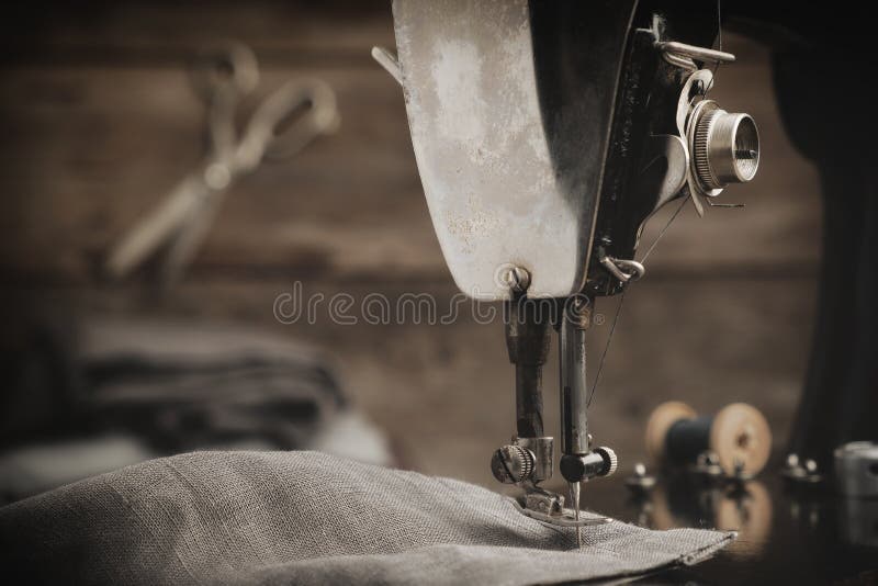 Antique sewing machine with linen cloth. In the background is a hanging tailoring scissors. Retro tailor workshop