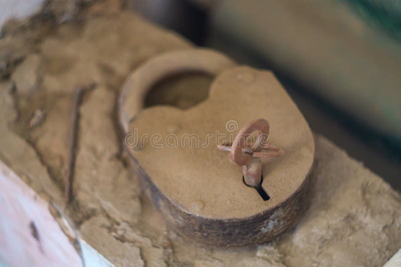 An old barn-type metal padlock with a key inserted into the keyhole lies on top of low brickwork. Covered with a layer of dust royalty free stock images