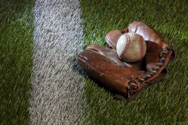 Old Baseball in Brown Leather Mitt on a Grass Field with a White Stripe