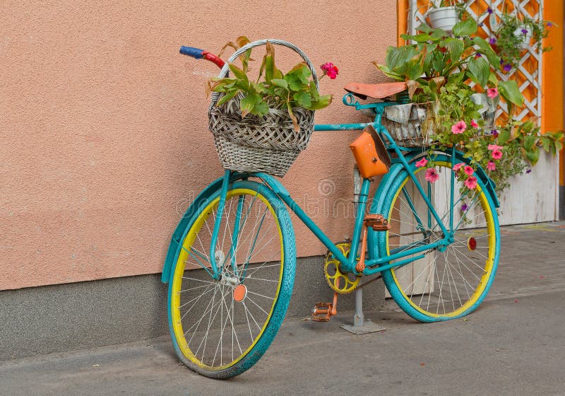 Old bicycle with flowers and a basket by the wall