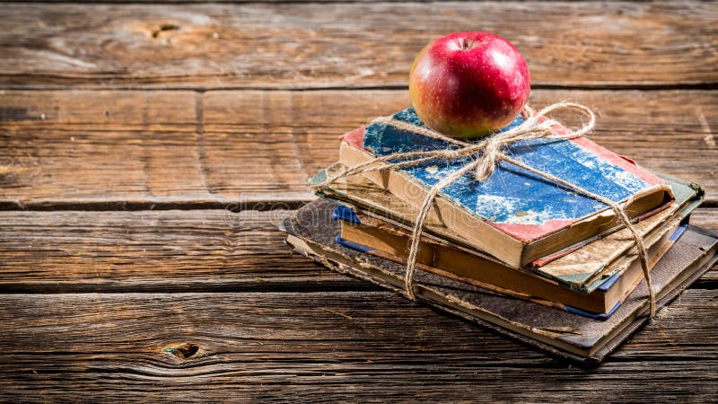 Old books and apple on school desk