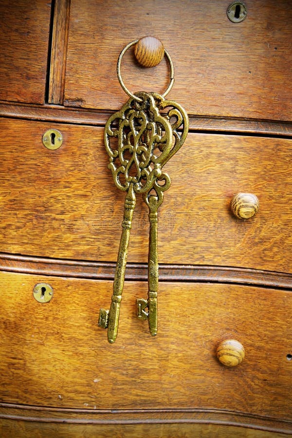 Old Brass Keys Hanging on Antique Bureau Dresser Drawer Pull royalty free stock photo
