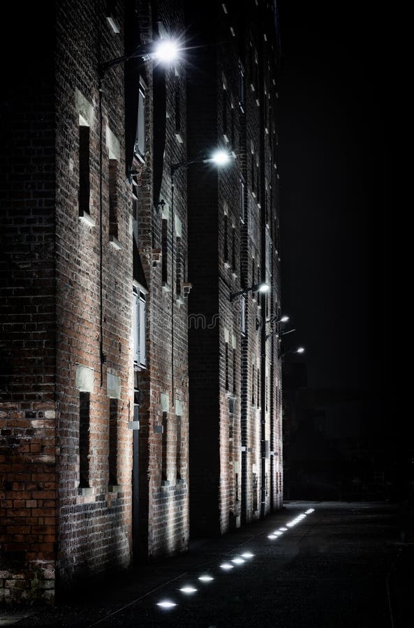 Old brick building illuminated by bright lamps at night stock image