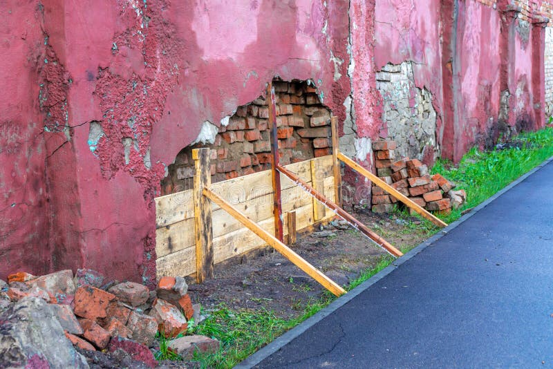 An Old Brick Wall Covered with Plaster is Falling Apart and it is Being