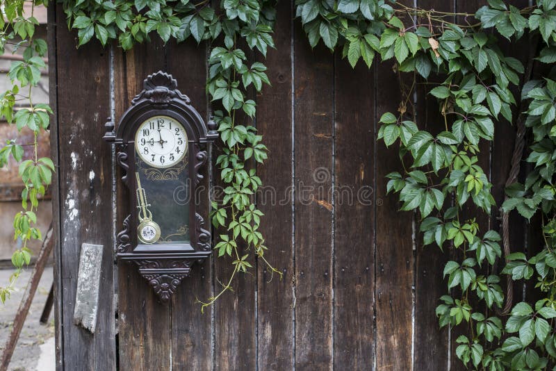 Old Broken Clock on the natural green leaf frame on wooden fence