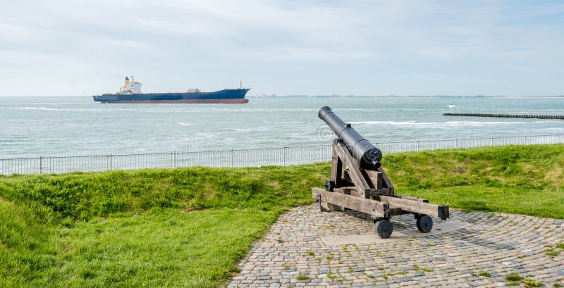 Old cannon focused on a passing freighter