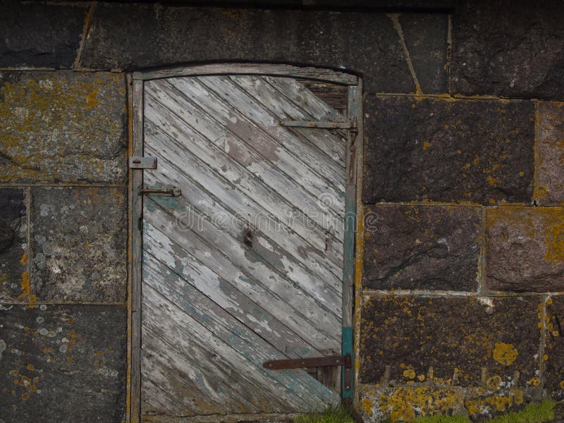 Worn wooden door on stoned wall. Worn wooden door on stoned wall.