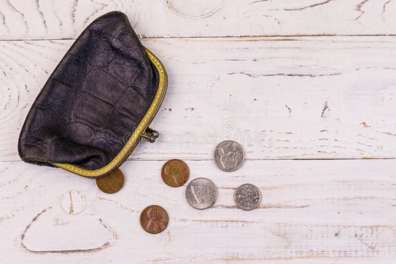 Old change purse with several coins on a white wooden background. Concept of poverty or bankruptcy