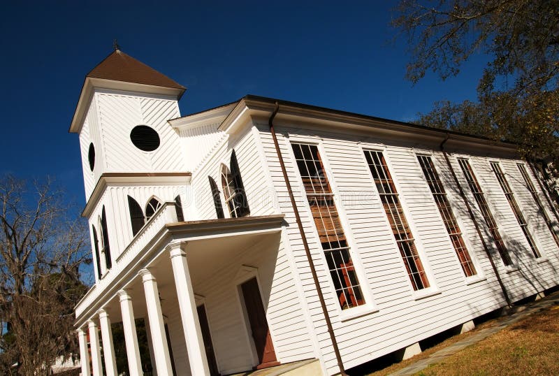 An old white church building in front of a blue sky. An old white church building in front of a blue sky.