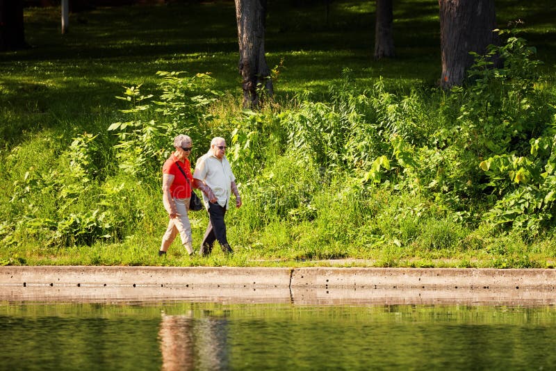 Old couple walking hand in hand near the pond in Park La Fontaine stock image Old couple walking hand in hand near the pond in Park La Fontaine stock image