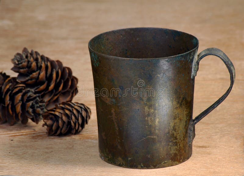 Old cup from a copper and fir-cones on a table