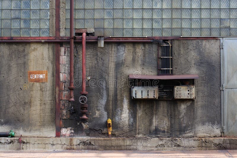 Old dirty factory wall with pipes and electricity central