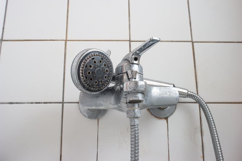 Old dirty limescale chalk covered shower head and bathtub faucet close up low angle view royalty free stock photography