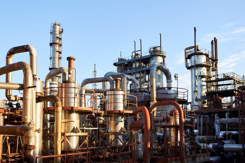 Old distillation column towers and reactors under blue evening sky background at chemical plant. Exterior of silver stock images