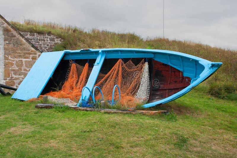 Old disused timber built fishing boat with nets and lobster pots on display