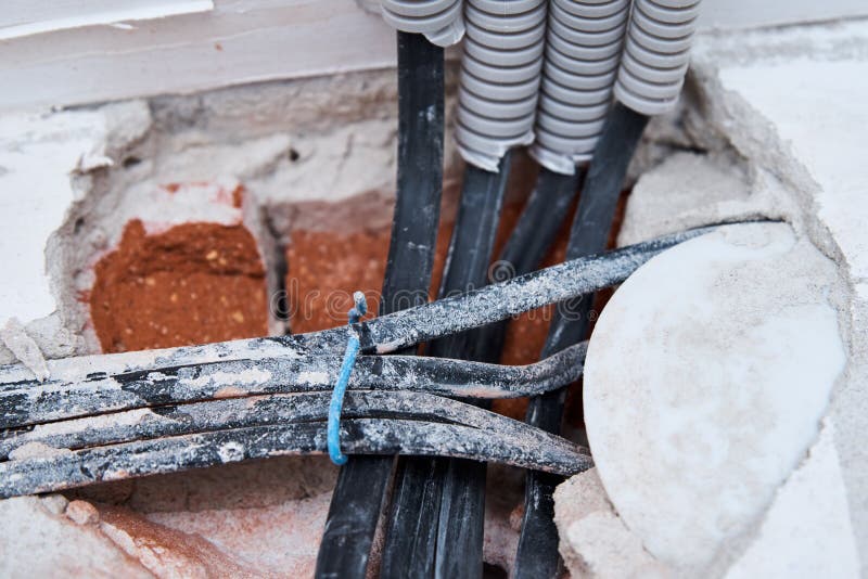 Old Electrical Cables in a Brick Wall. Danger Wiring Stock Image