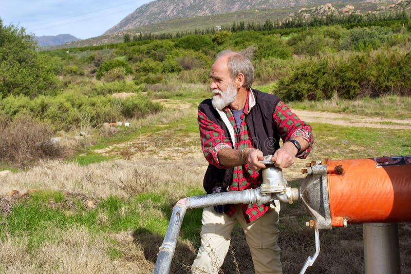 Old farmer regulates water pipe stock images