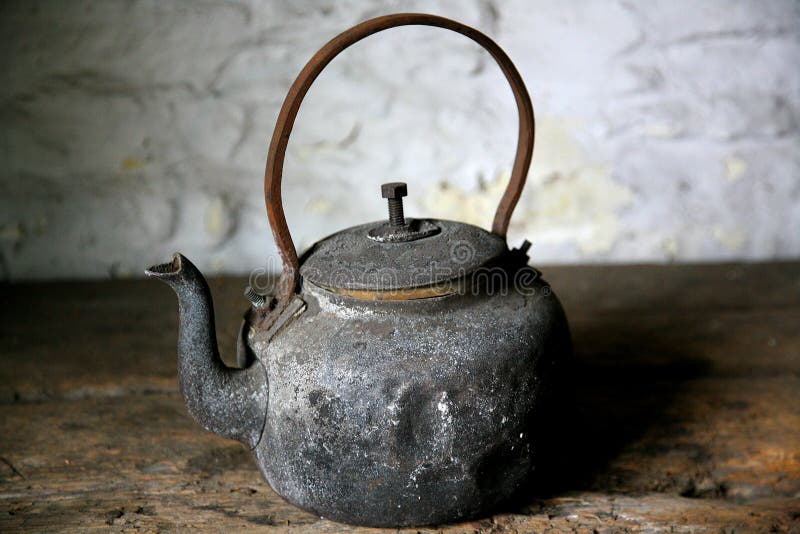 Old fashioned rusty black kettle on a wooden bench