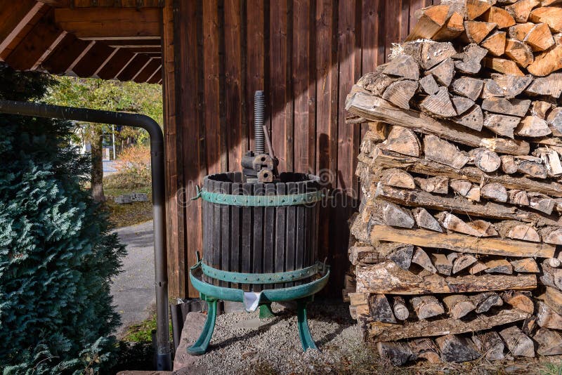 Old fashioned wine press next to pile of logs