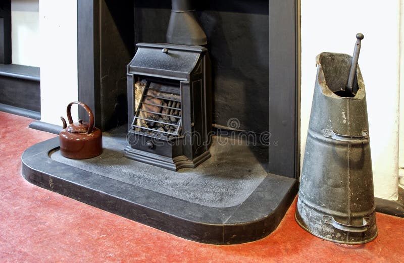 Old fireplace, grate, coal scuttle and enamel kettle in an old h