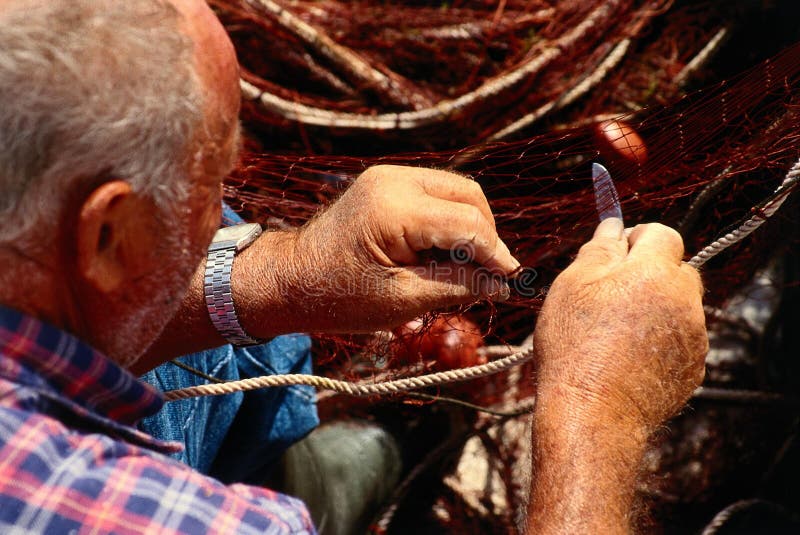Old fisherman mending net