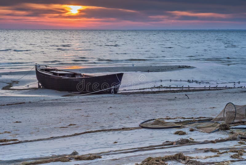 The old fishing boat on the beach of Baltic sea at sunrise