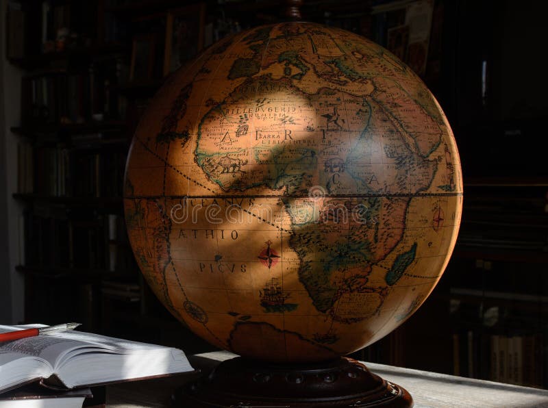 An old globe is standing on a table in a library