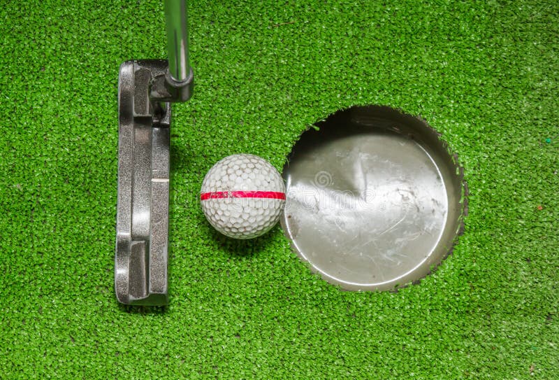 Old golf balls and putter on artificial grass.